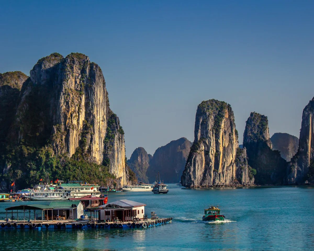 Karst islets rise out of the water with cruise ships navigating the blue waters