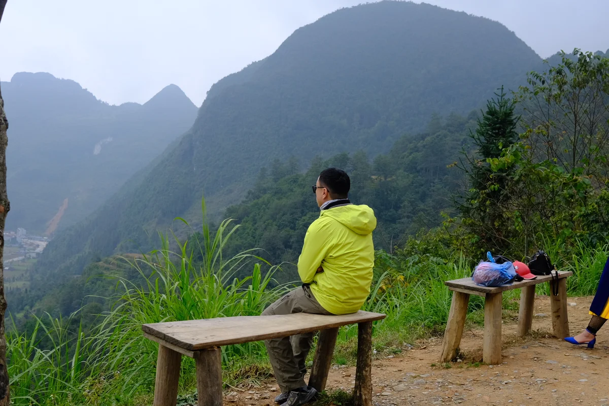 A man sitting on a bench looking at the mountain scenery in the distance