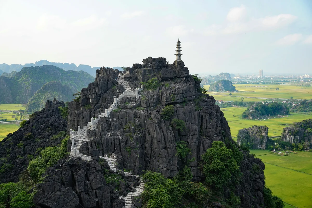 Steps up to a mountain top with a pagoda and greenery all around