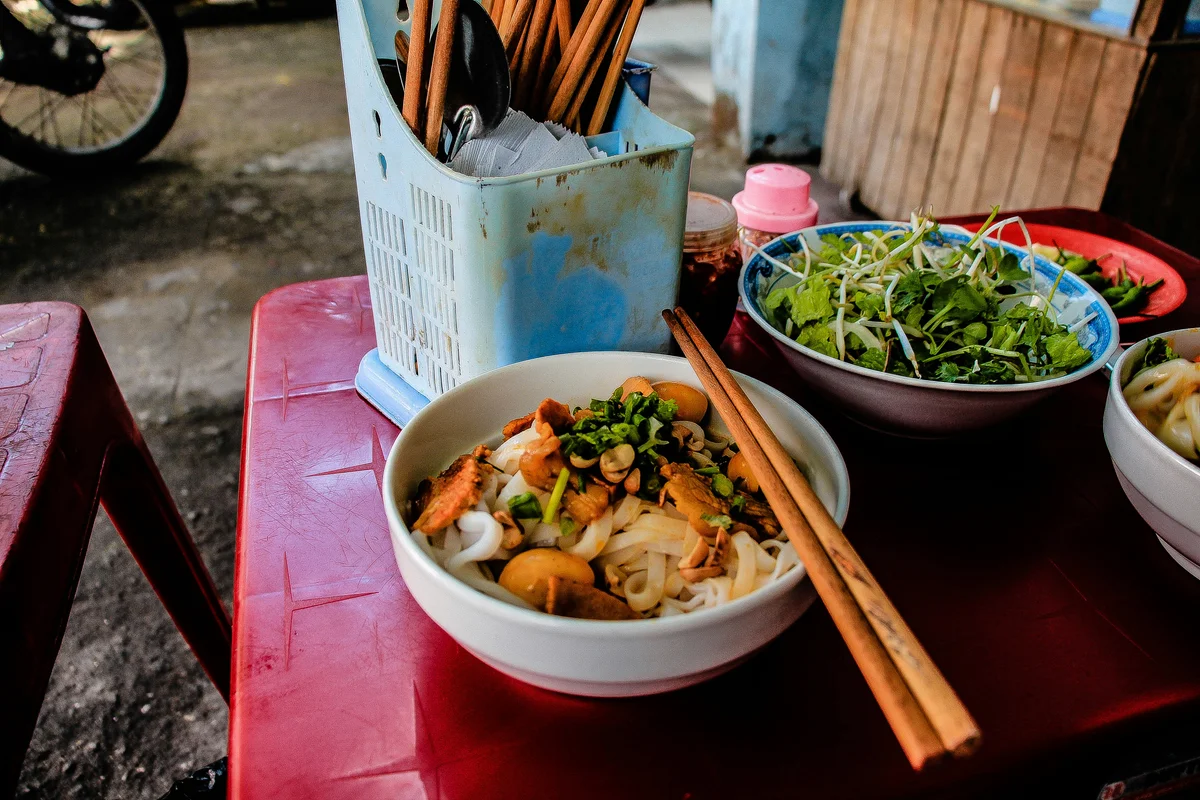 Two bowls filled with food on a table with chopsticks laid across the bowl