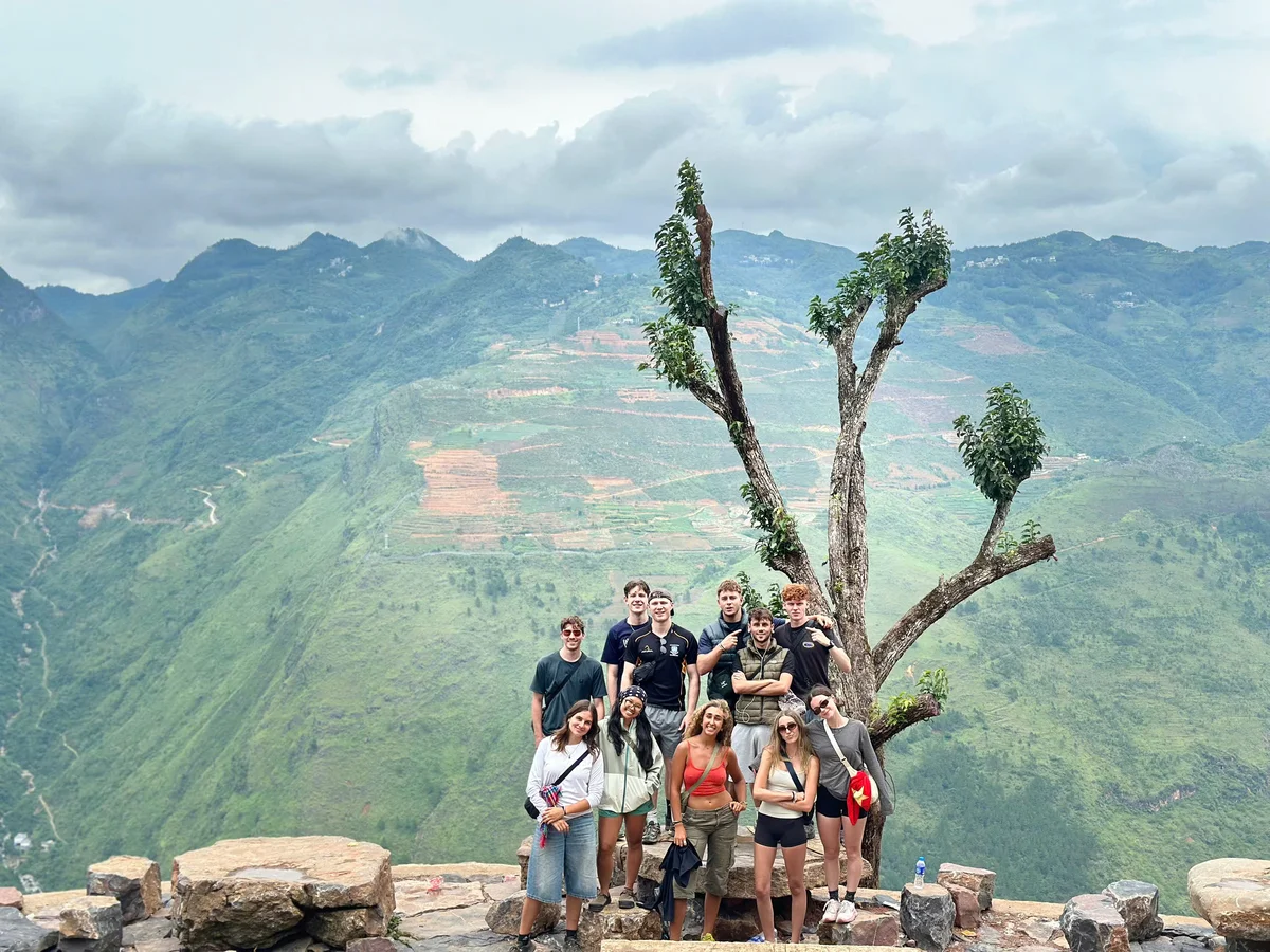 Group of people posing by a tree with mountain backdrop