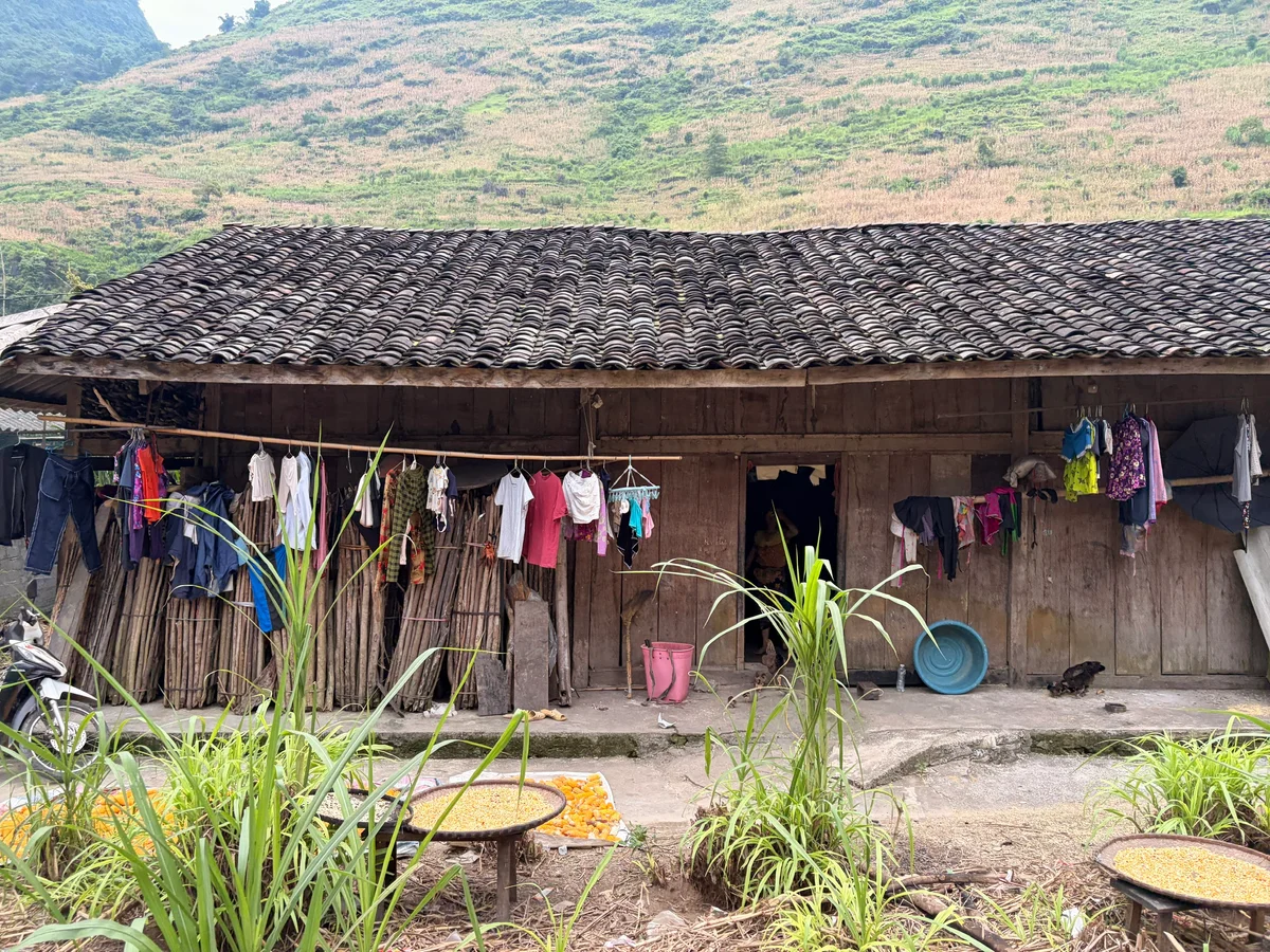 A traditional wooden house with colourful washing hanging in front and shrubbery