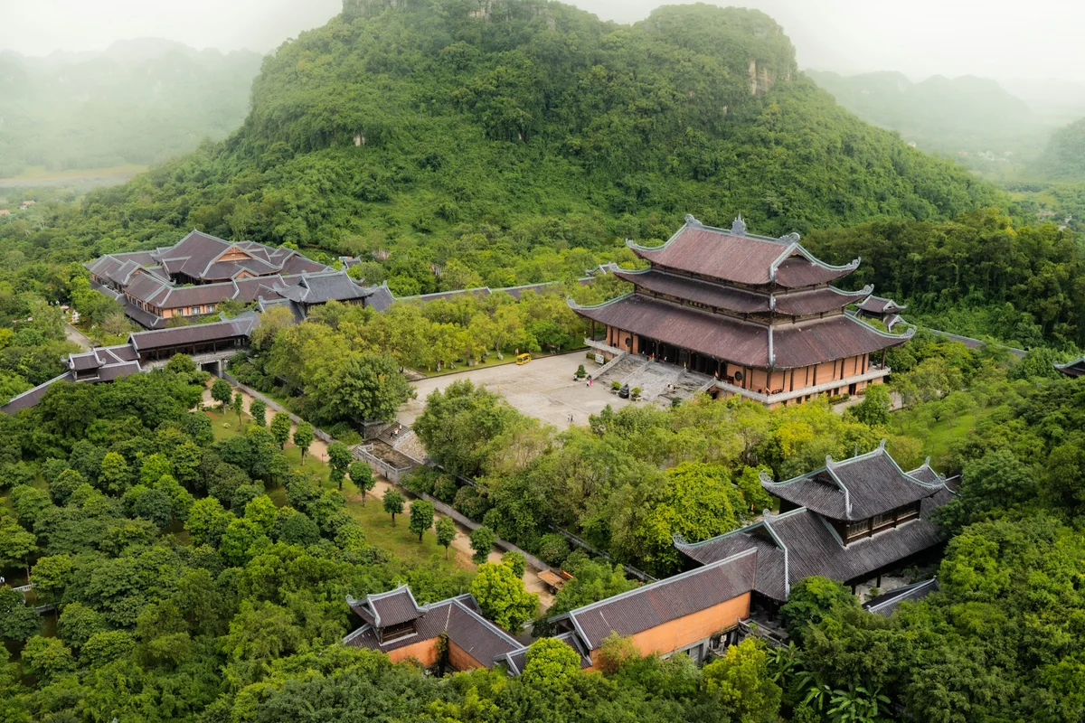 Temples enclosed in nature with trees and mountains and mist surrounding the buildings