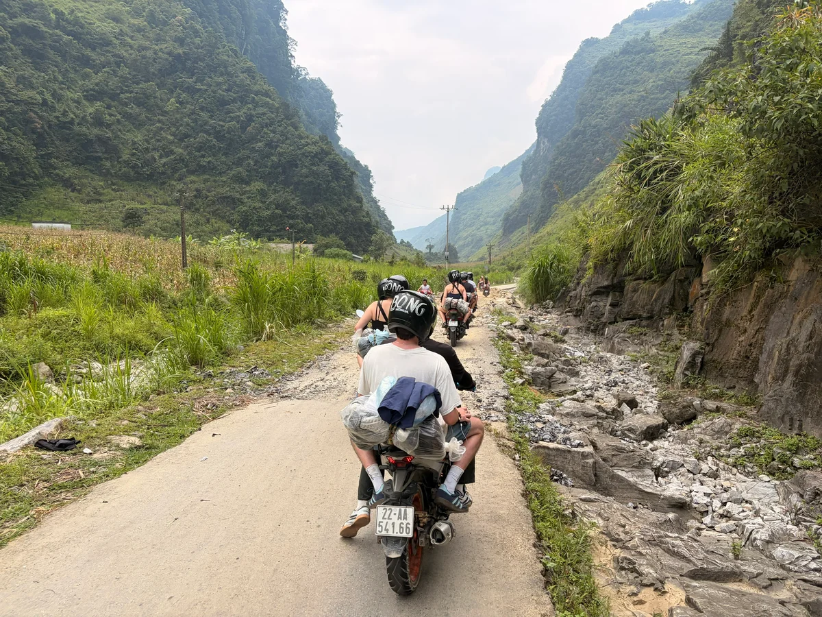 A man on a motobike takes a photo of mountain scenery surrounding them
