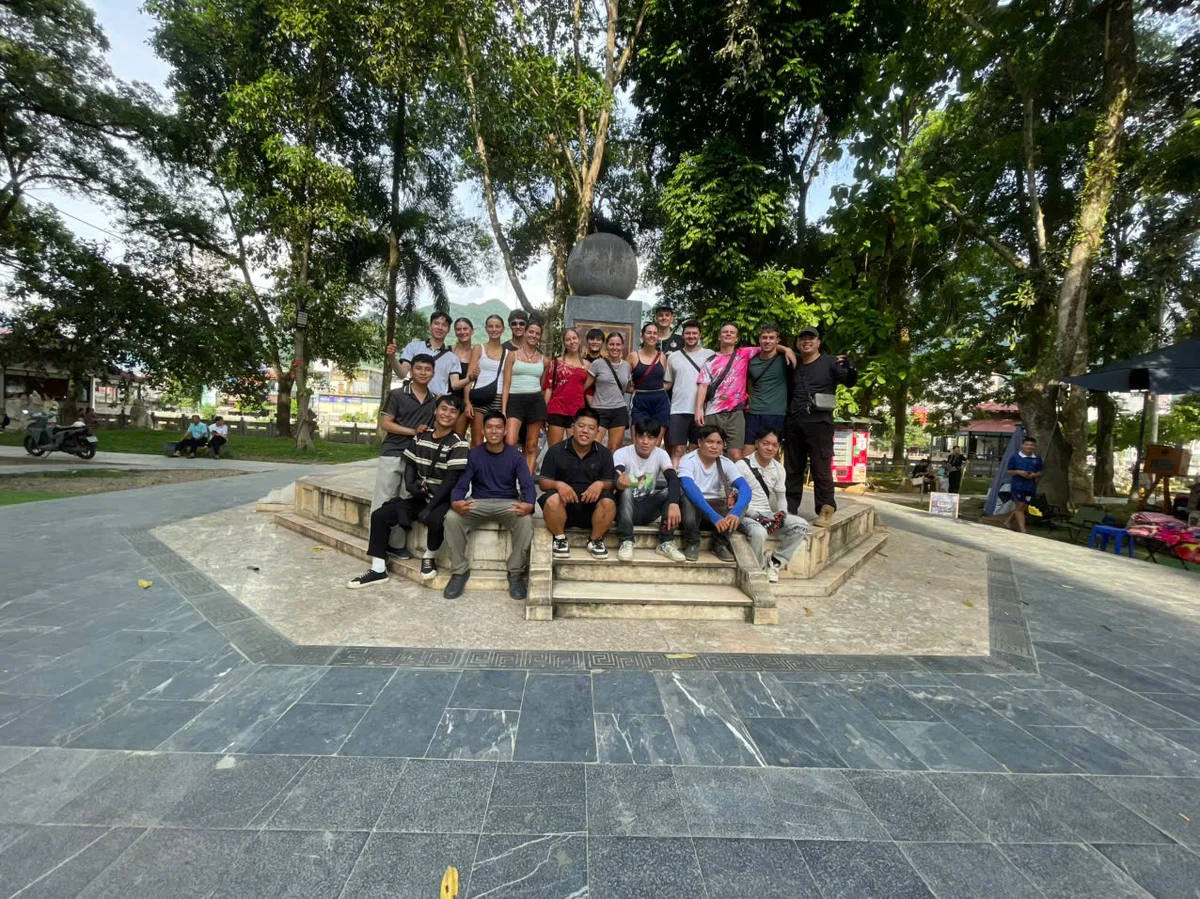 A group of people pose by a pillar that says KM0