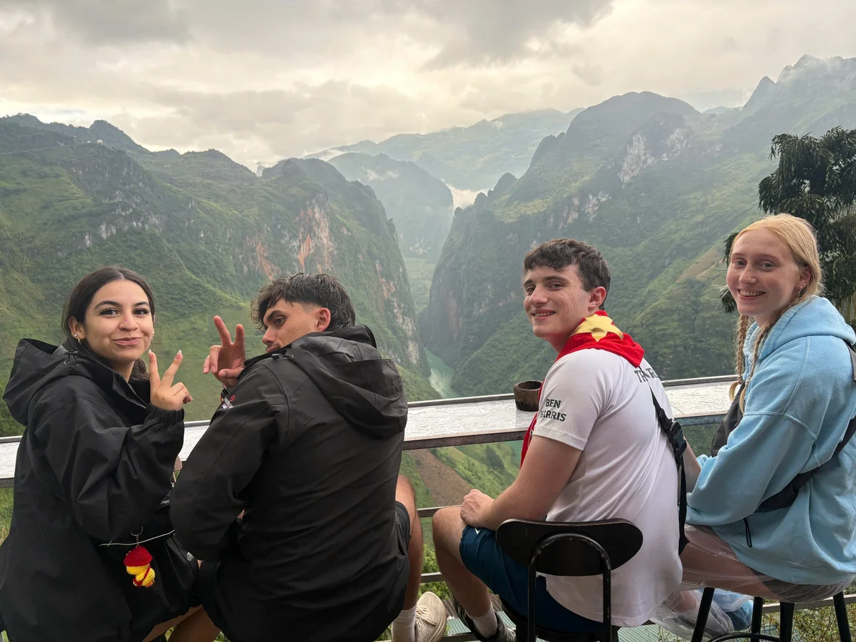 People sitting at a wooden table overlooking a river below