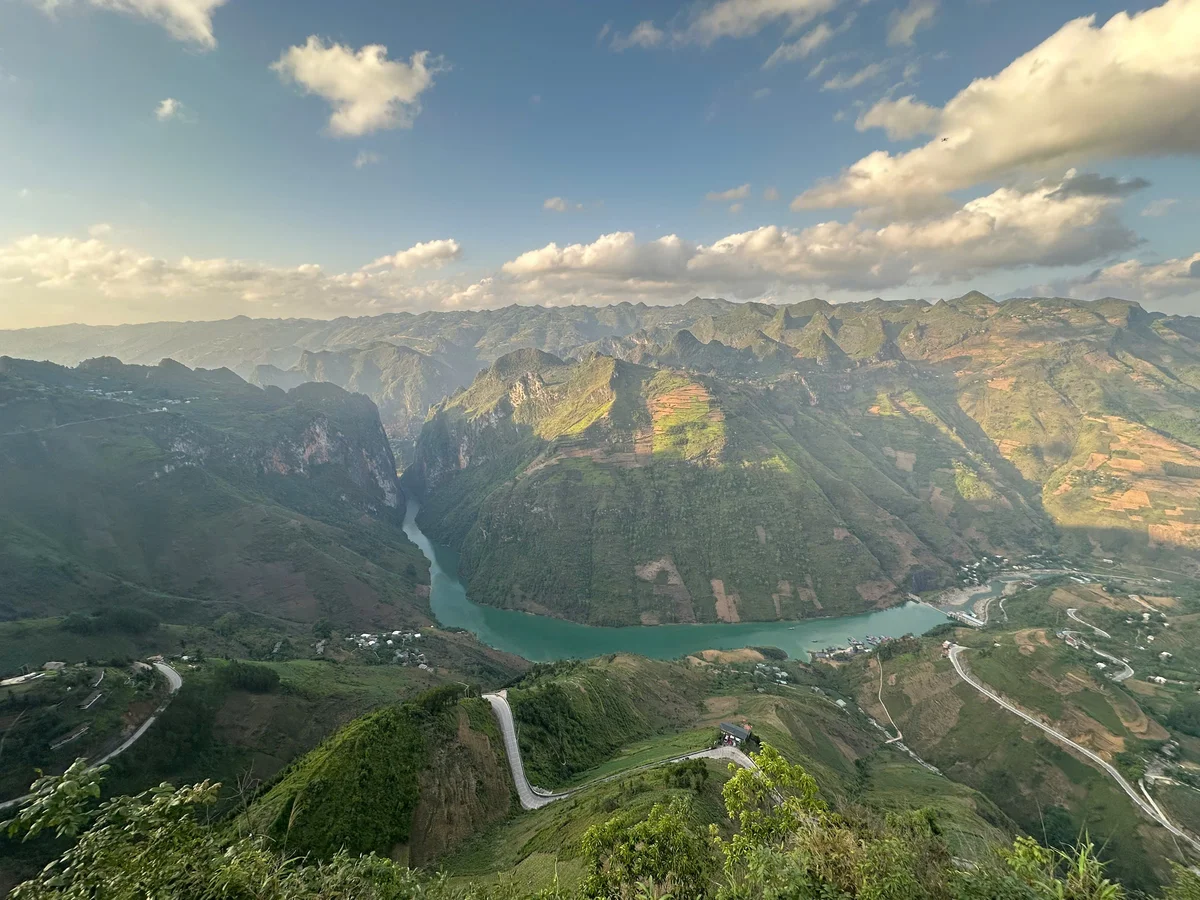 A landscape shot of karst mountain scenery, blue skies, clouds, sunshine, and a winding blue ribbon of water stretching below