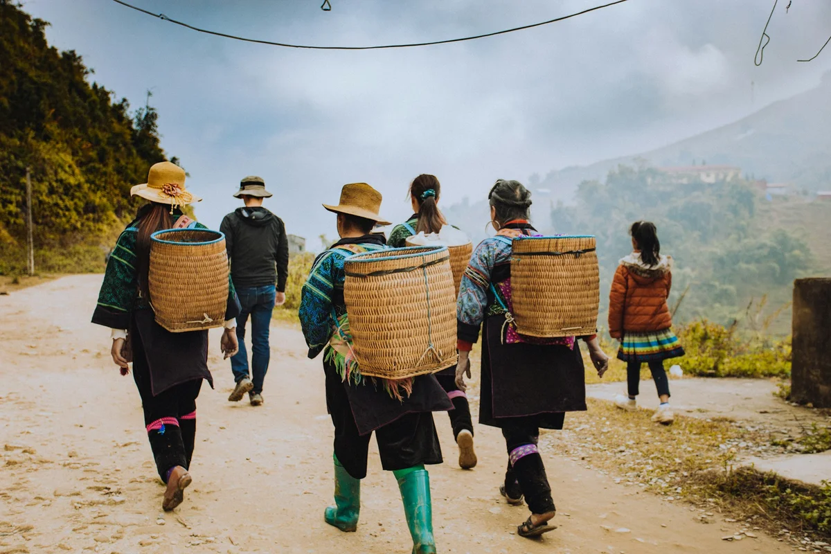 Women trekking in traditional clothing carrying baskets on their backs