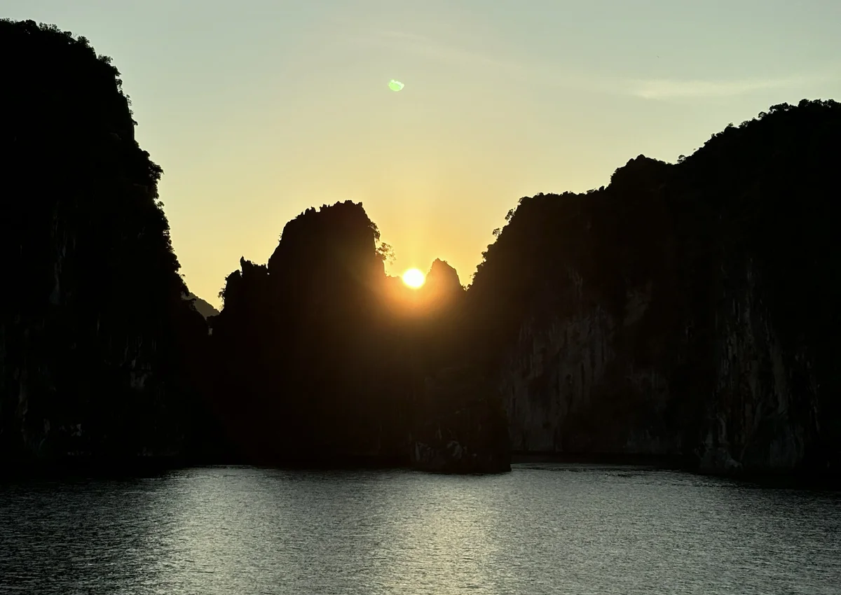 Sun setting between karst islets over the water