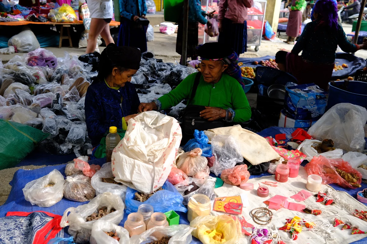 Two women sit selling their wares at a local market