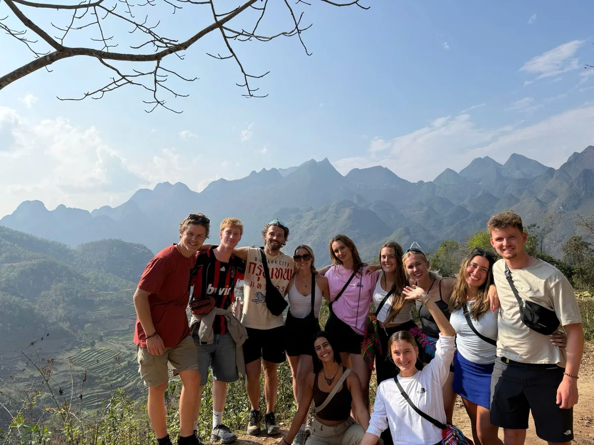 Group of people posing with mountains behind and blue skies