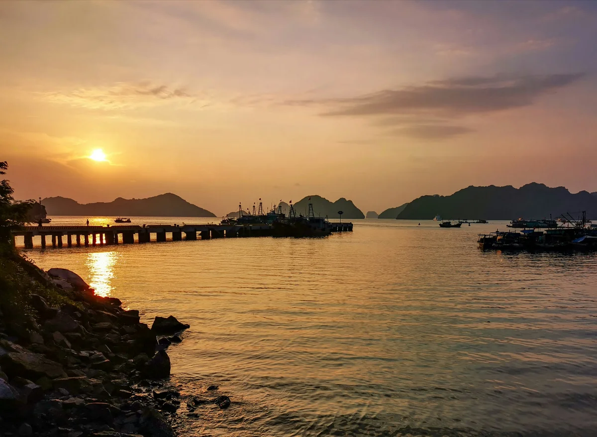 Sunsetting over ocean, islands, and boats dot the periphery of the picture