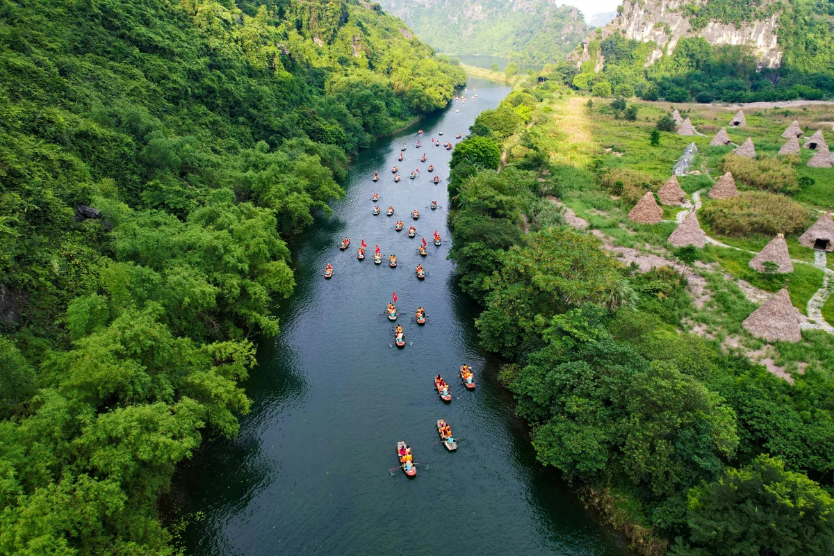A waterway cuts through trees with boats drifting along