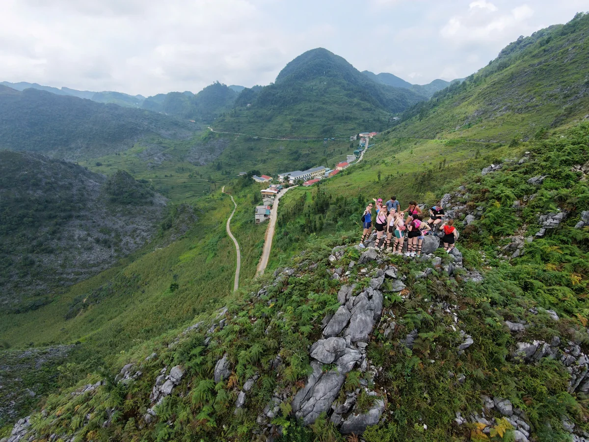 Green mountains with groups of people standing on slippery looking pathways