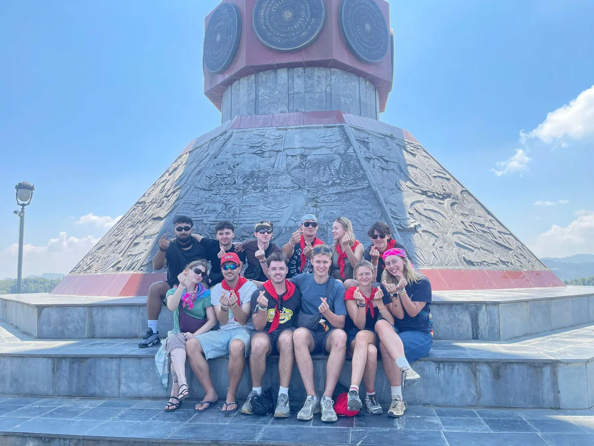 A group of people sit beneath the Lung Cu Flag Tower