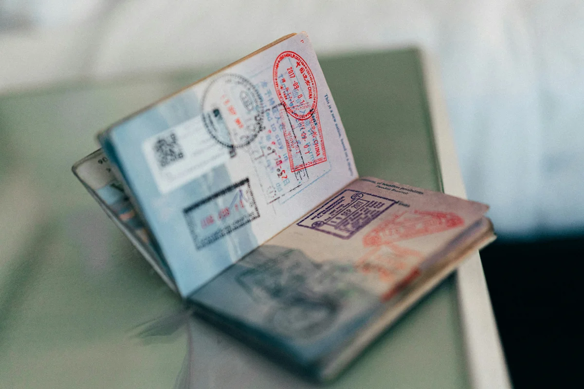 A passport lies open on a table with visa stamps on both pages