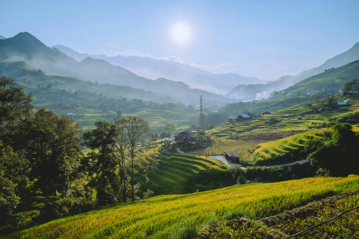 Sun shining above beautiful mountains with flowing terraced rice fields