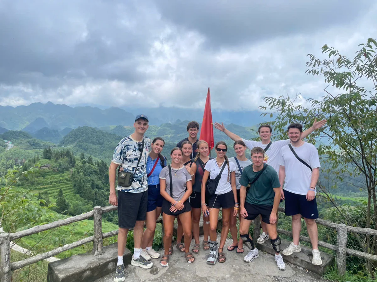 A group of people by a railing overlooking a panoramic view of mountains