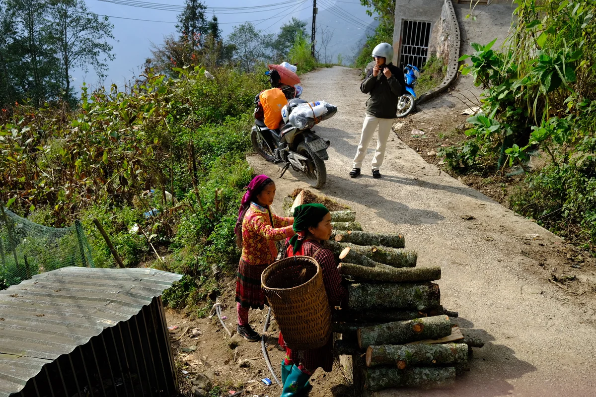 People in colourful clothing distribute items along a roadside