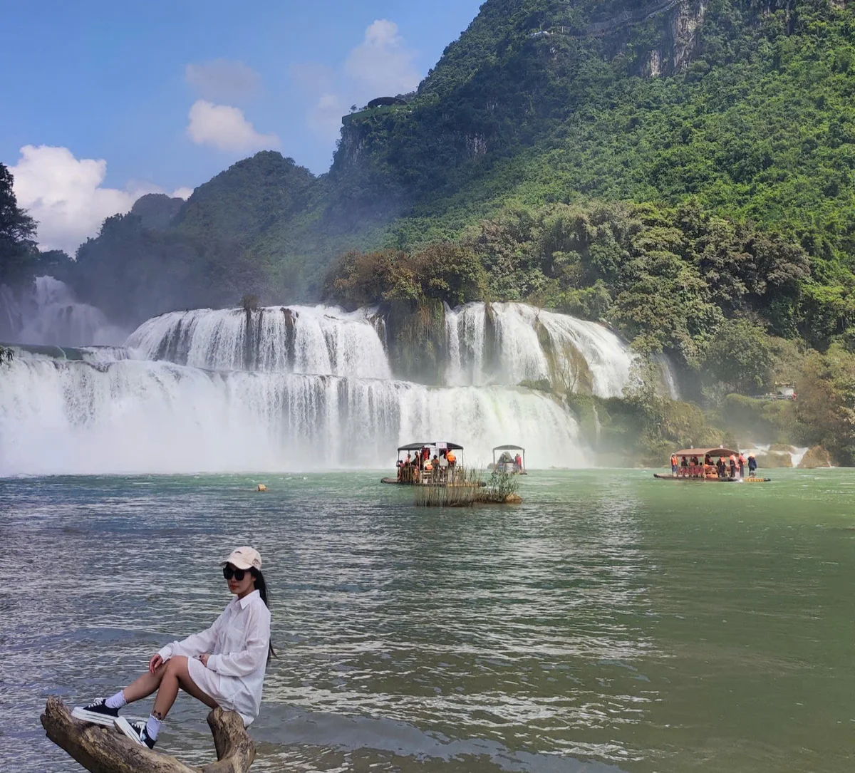Women posing with boats in the background at the Ban Gioc Waterfall, Cao Bang