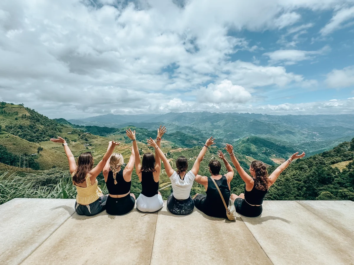 Six girls throwing their hands up with mountains in the background