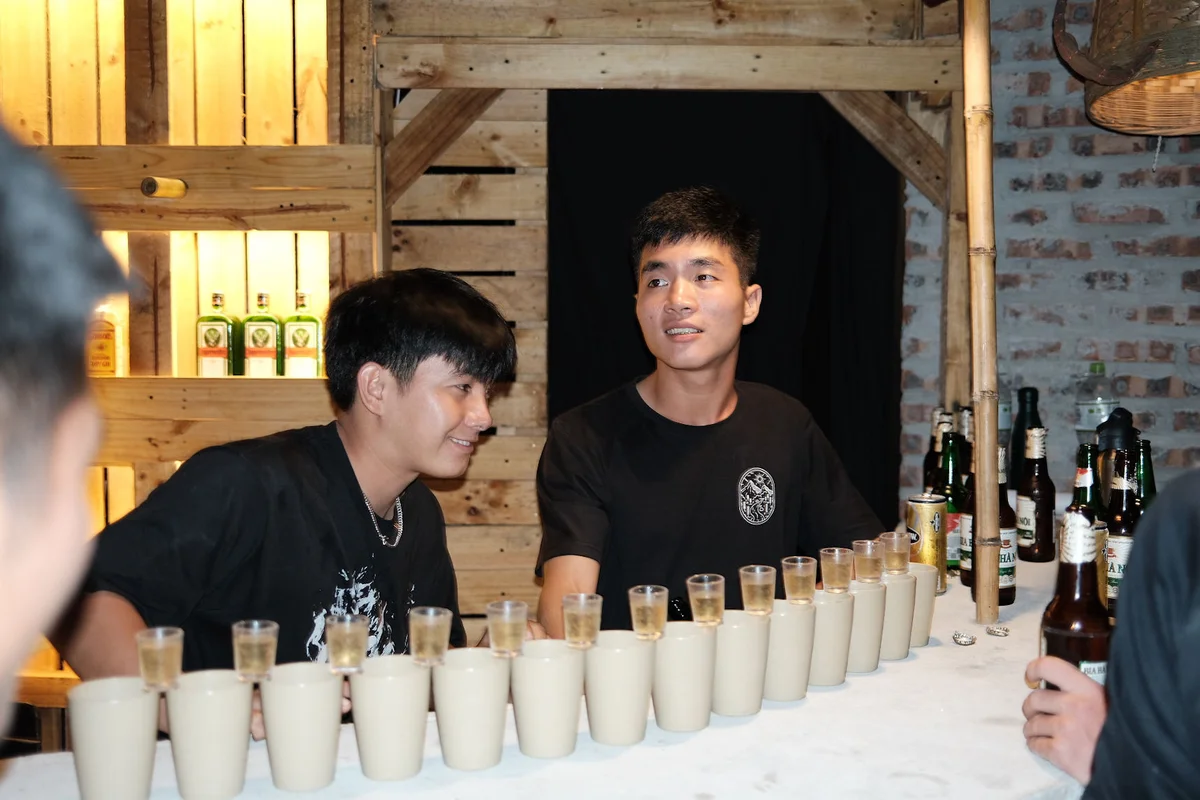 Two men pose with shots of alcohol