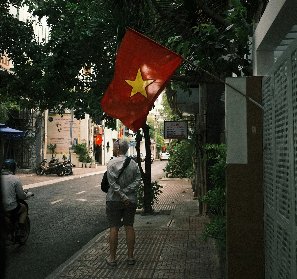 Lady walking beneath Vietnamese flag in Vietnam