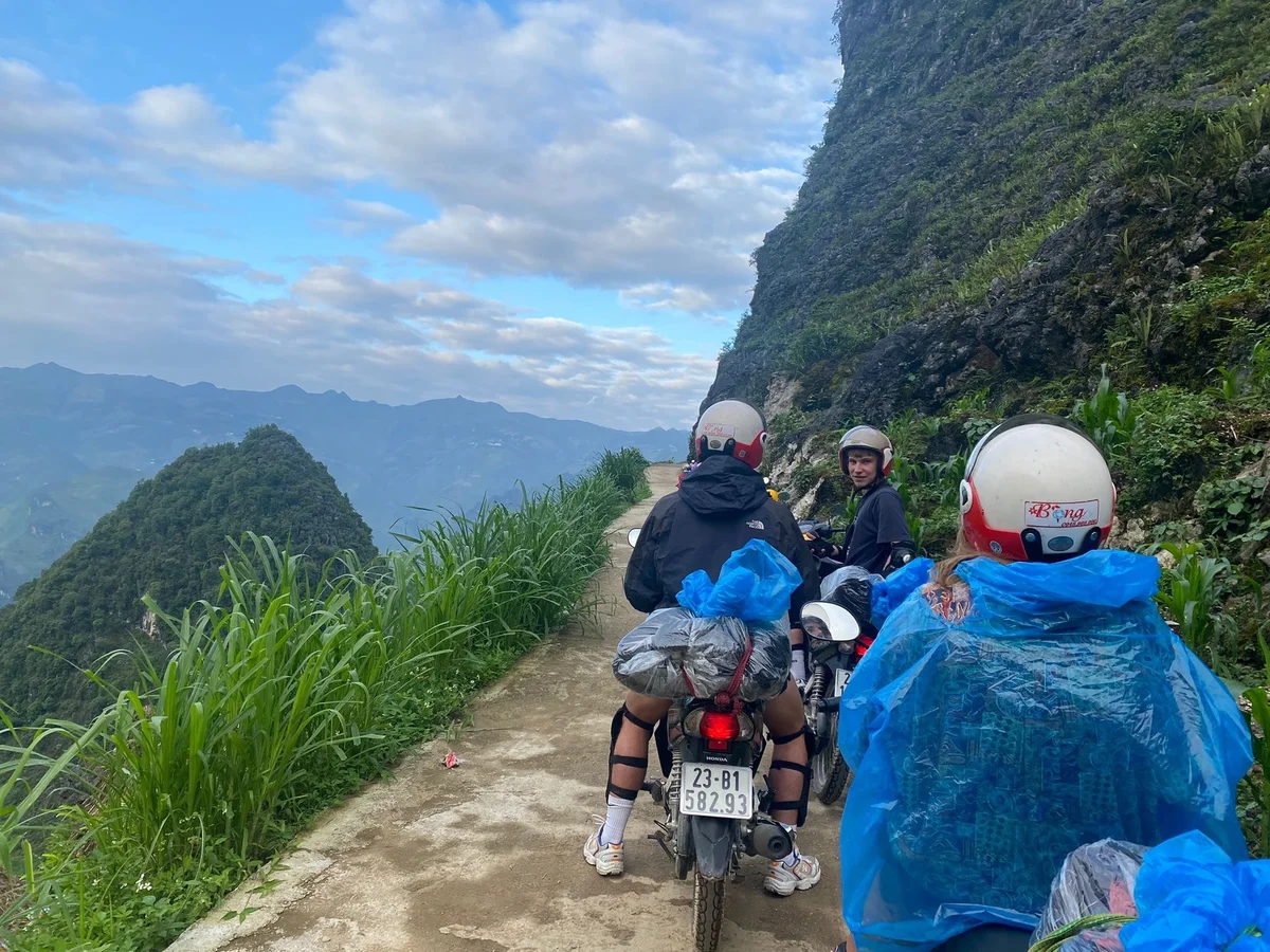 Three peopl on motorbikes with steep cliff edge next to them