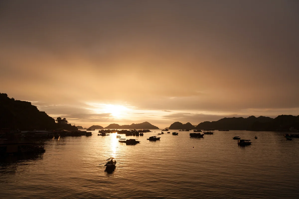 Sunset over the water with fishing boats and small islands visible