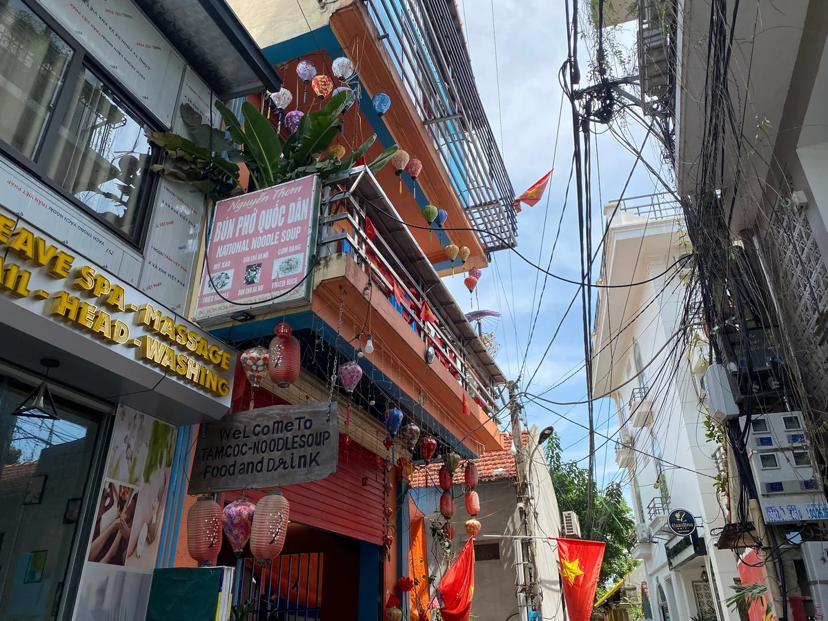 Winding street with restaurants and lanterns and electricity wires all around