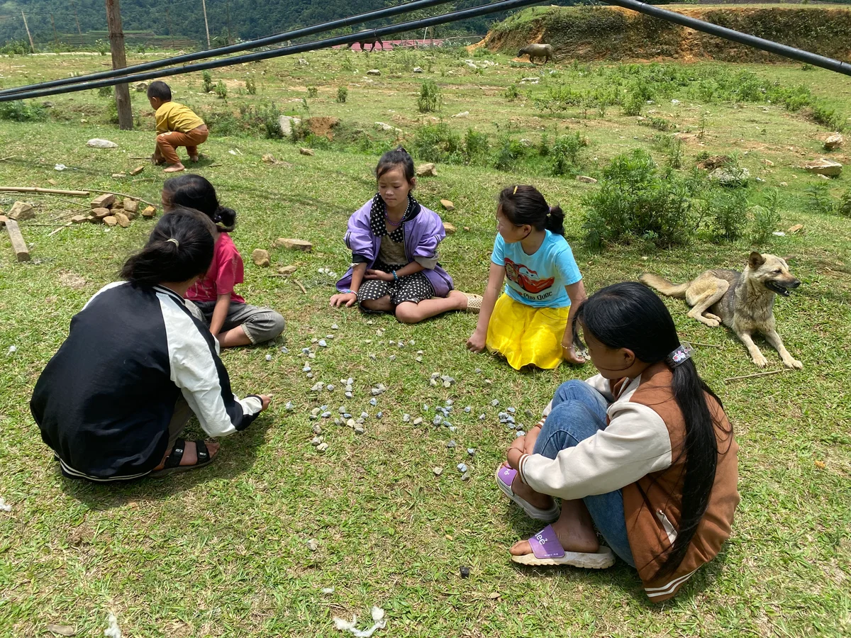 Children sitting playing with flowers in a field
