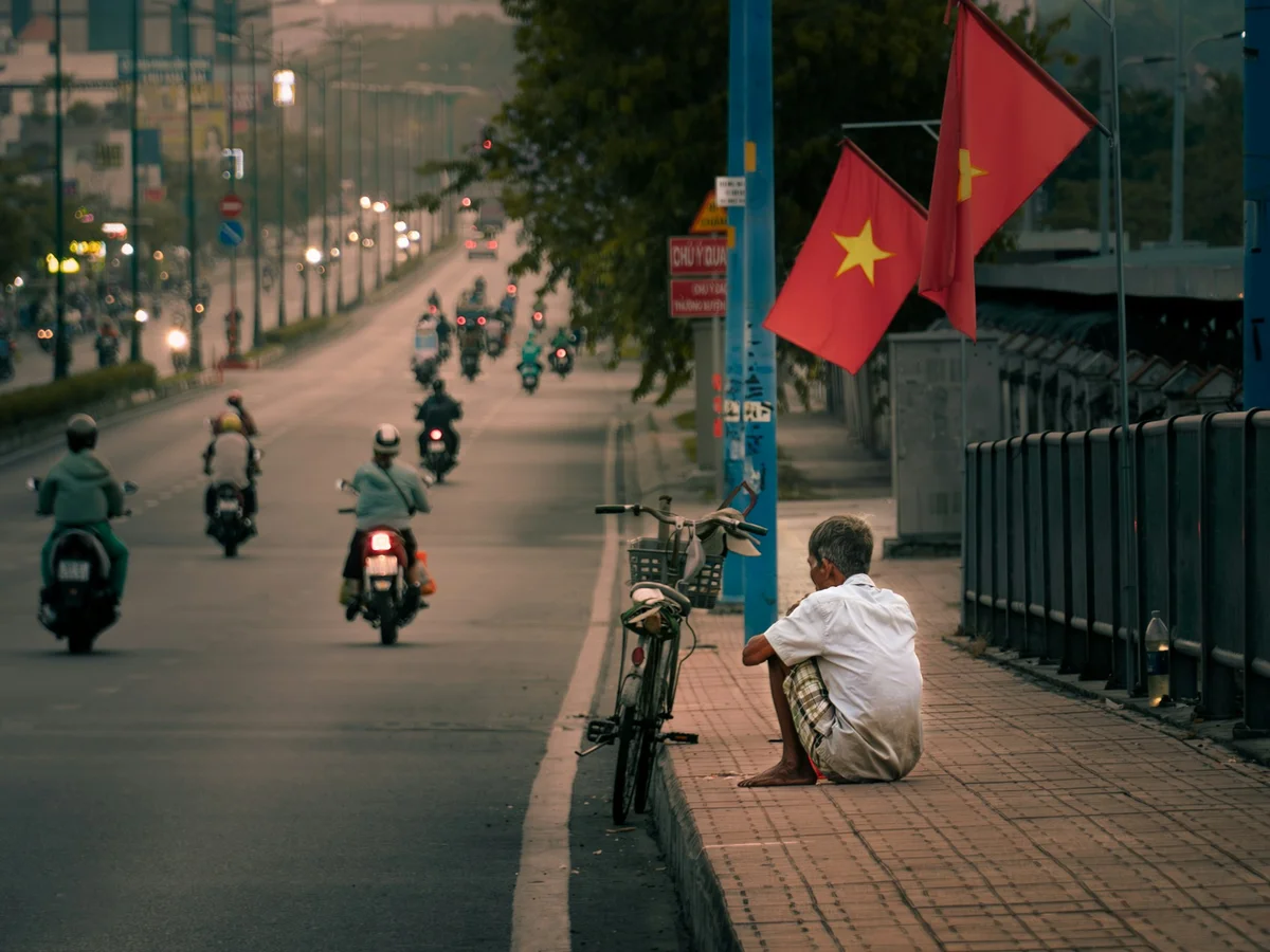 Man taking a rest by the side of a busy road in Vietnam