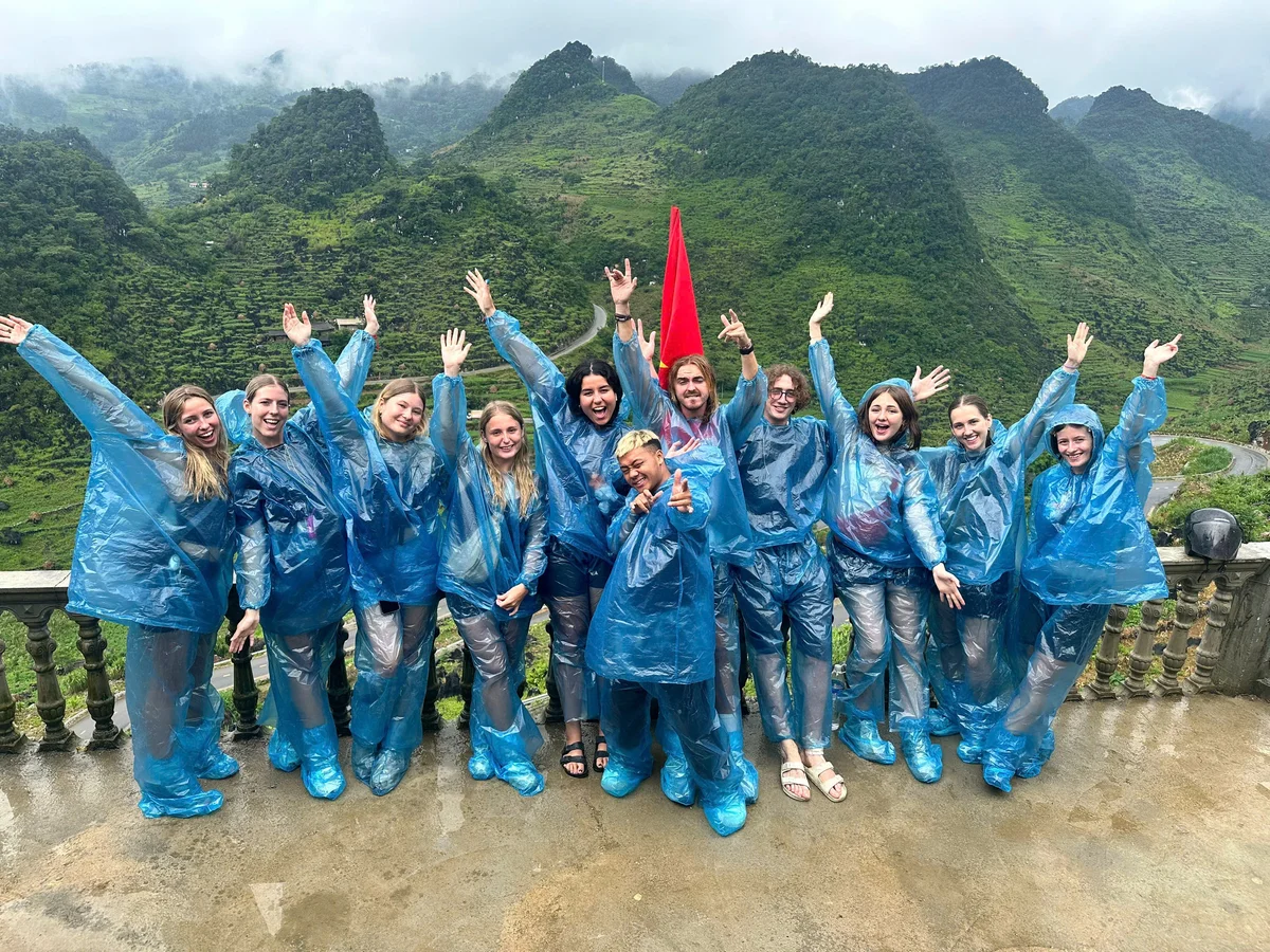 Group tour throwing hands up with rain ponchos on
