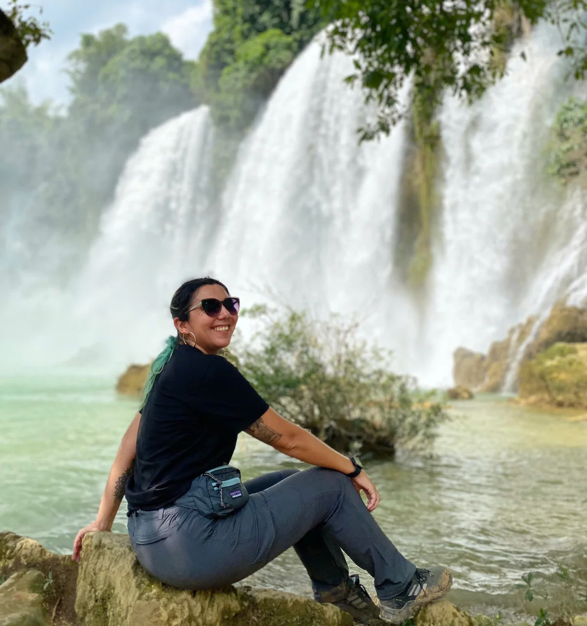 Woman posing and smiling by the Ban Gioc Waterfall