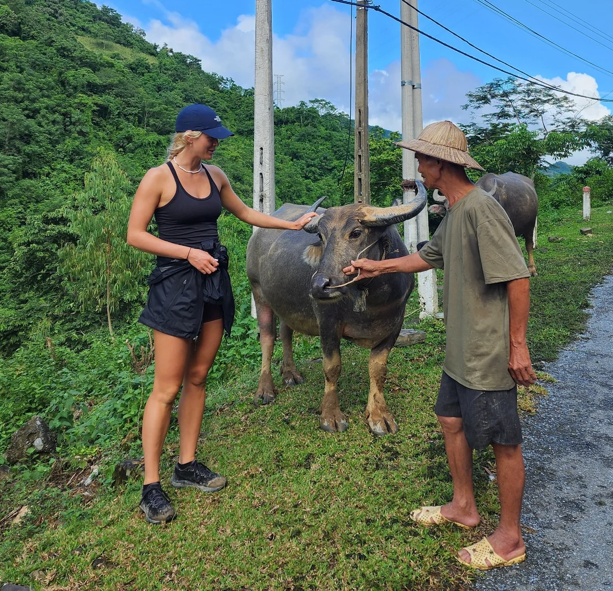 A woman pets a buffalo while a local man holds the animal