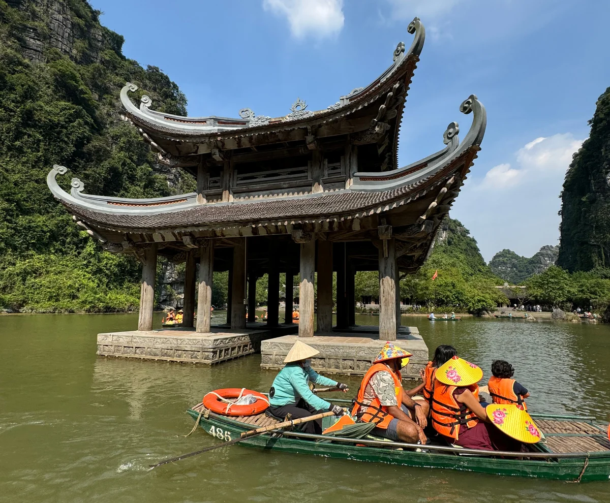 Ancient Temple on the Trang An river, boat of people infront