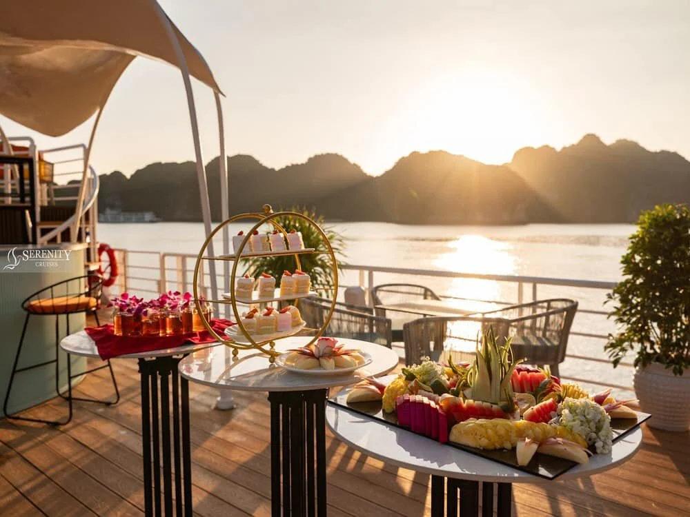 Sunsetting over the cruise deck, where there is a table laid with cakes and fruit
