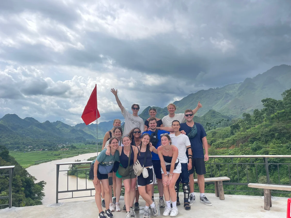 Group smiling on a viewing platform with mountains behind