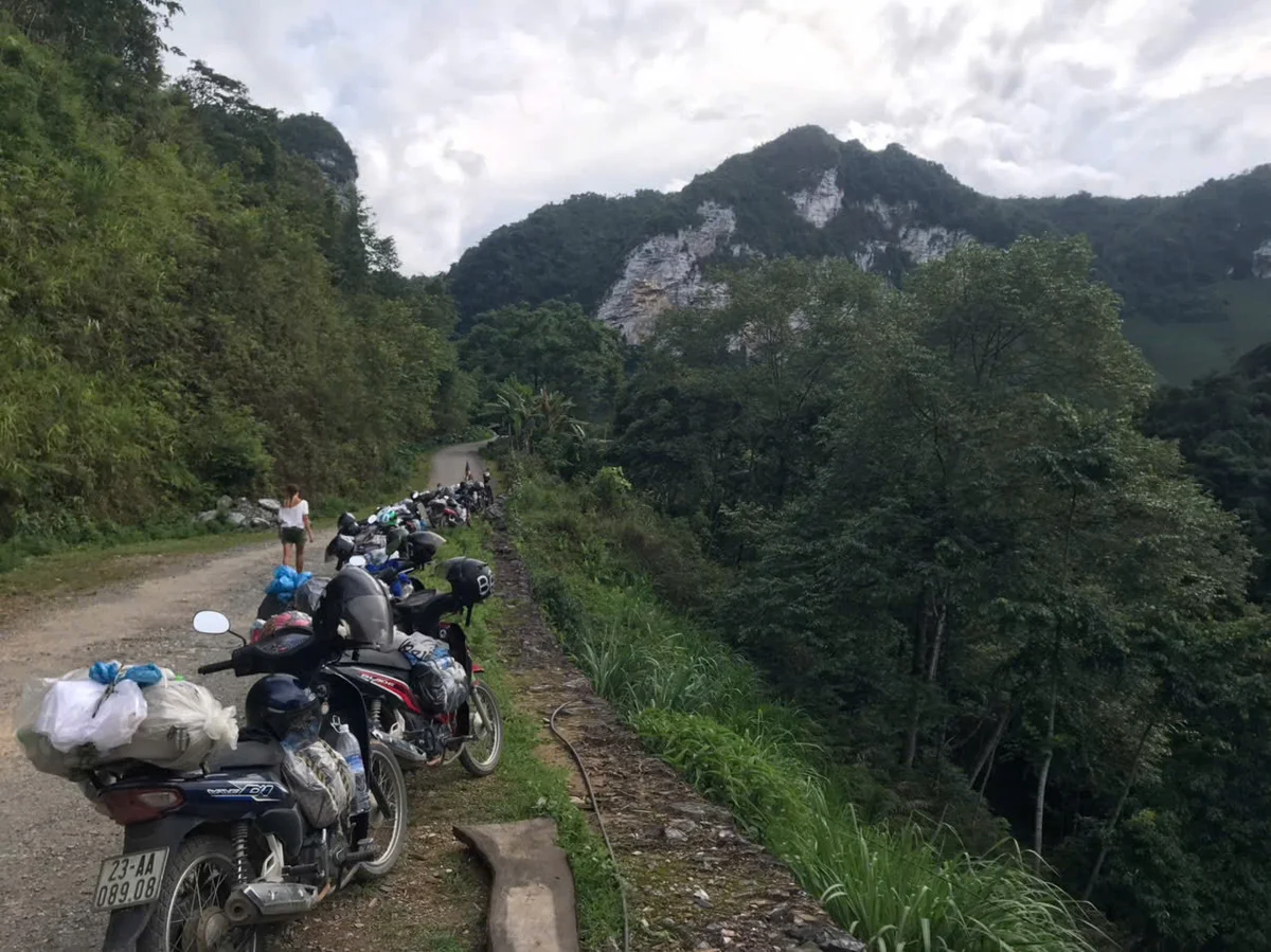 Motorbikes are lined up along a dirt path