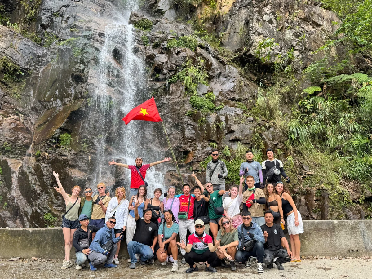 Group of people pose by a waterfall