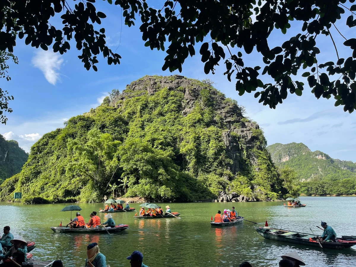 Sampan boats dotted along a river with a karst mountain in the background