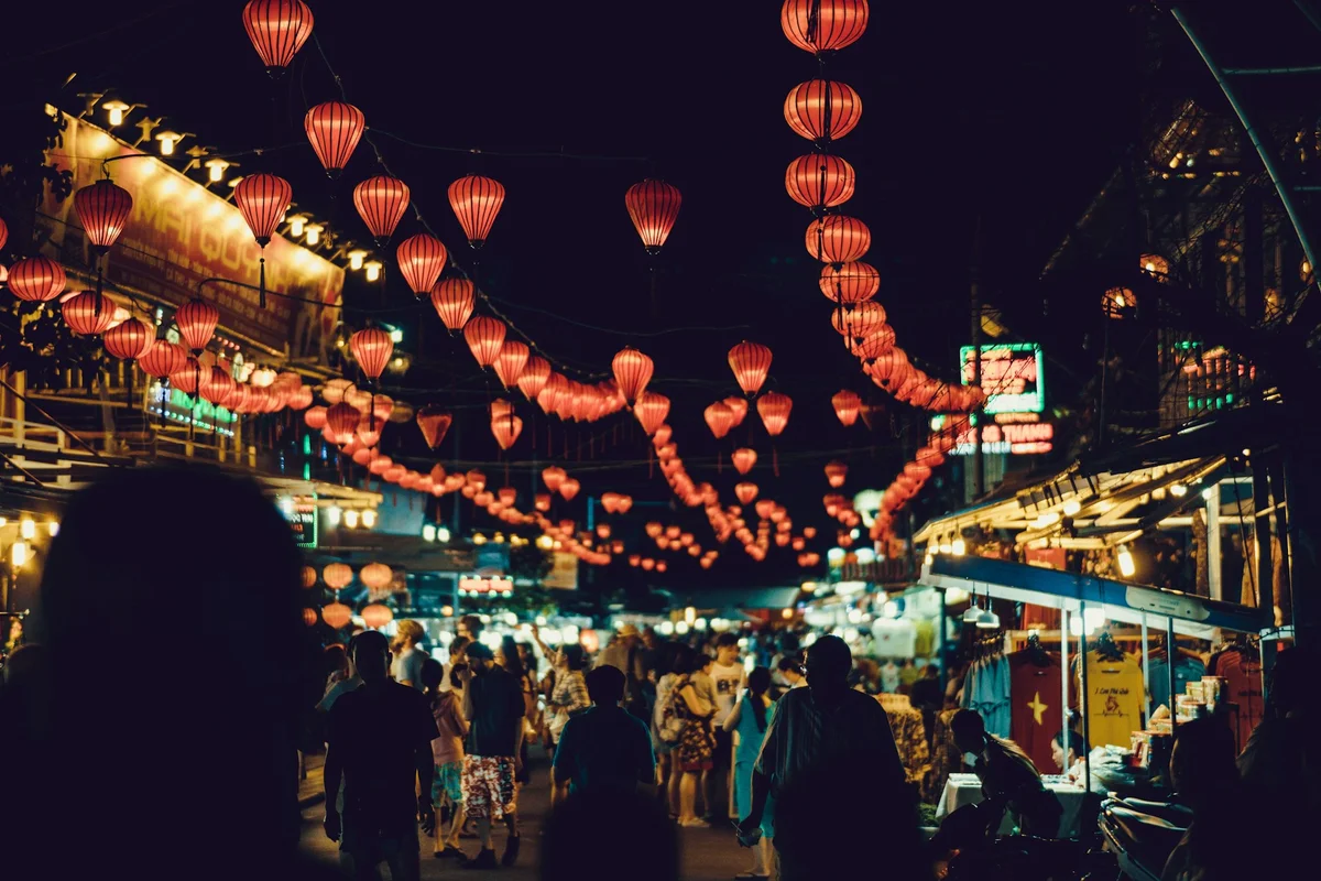 Lanterns and people walking through a street market in Vietnam