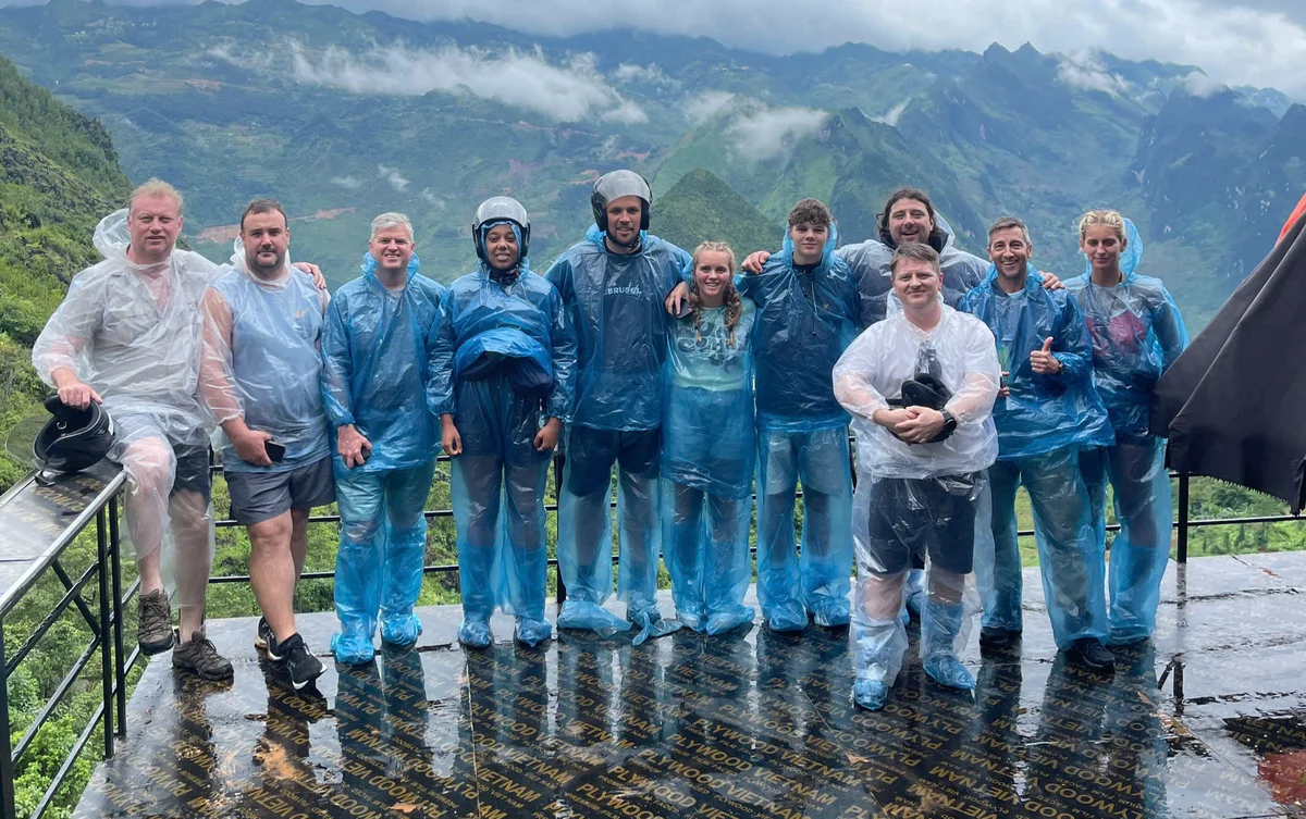 Bong Hostel Group tour in rain gear pose at a scenic viewpoint 