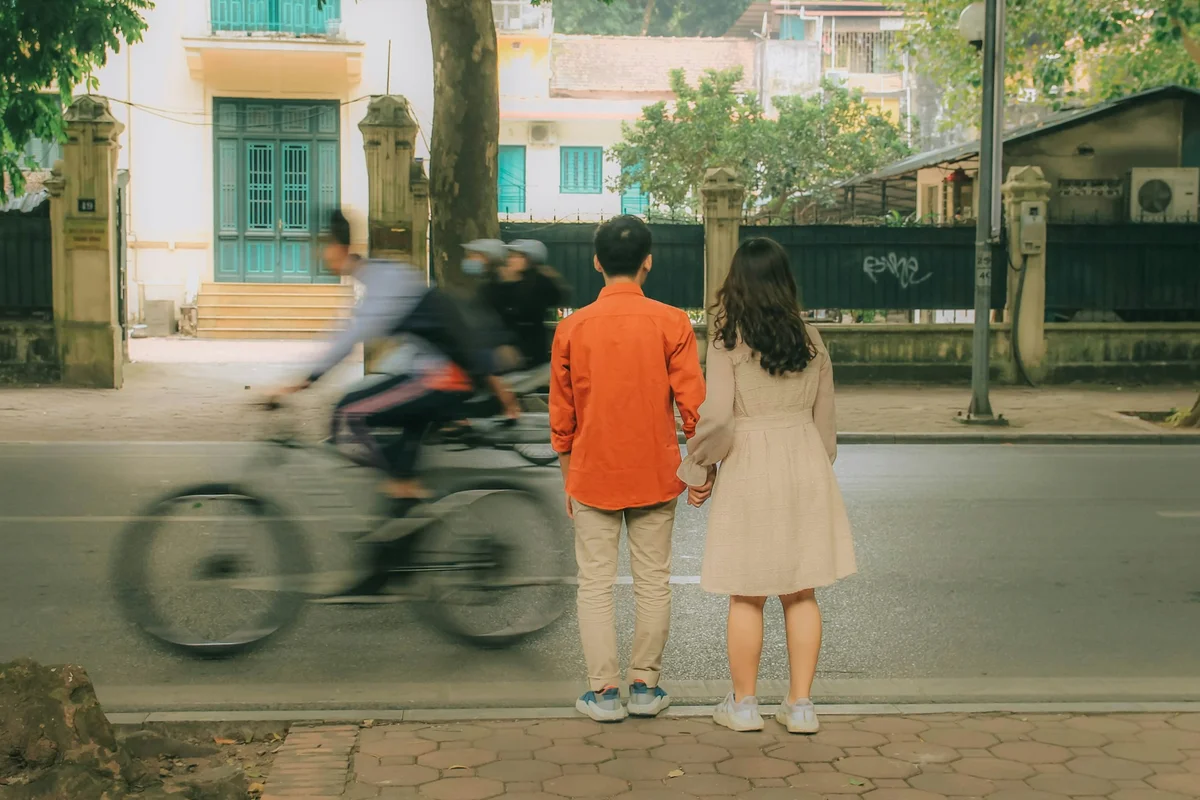 Couple standing hand in hand waiting to cross the street in Hanoi