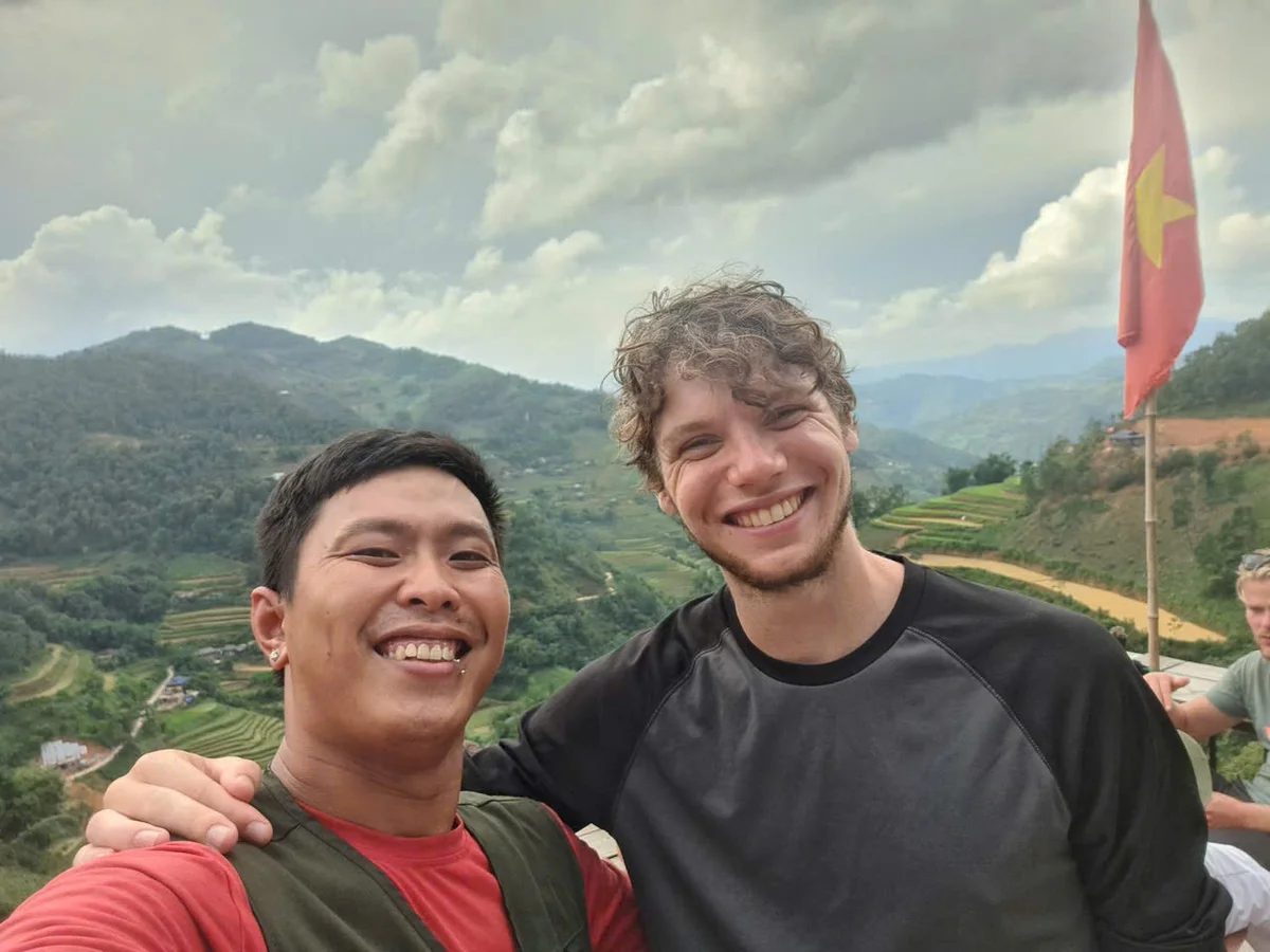 Two people pose in front of clouds and rice terraces