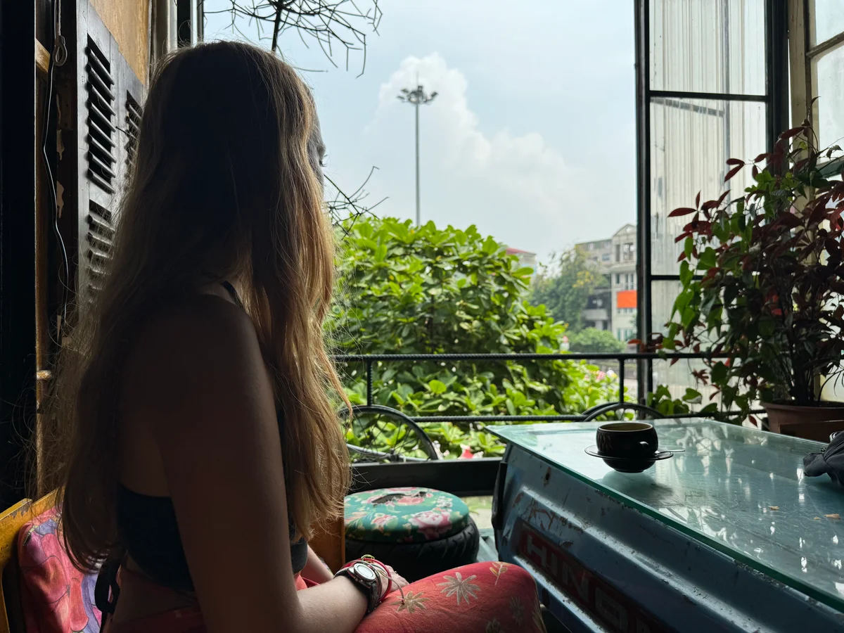 Woman sitting in a coffee shop window looking out to Hanoi city