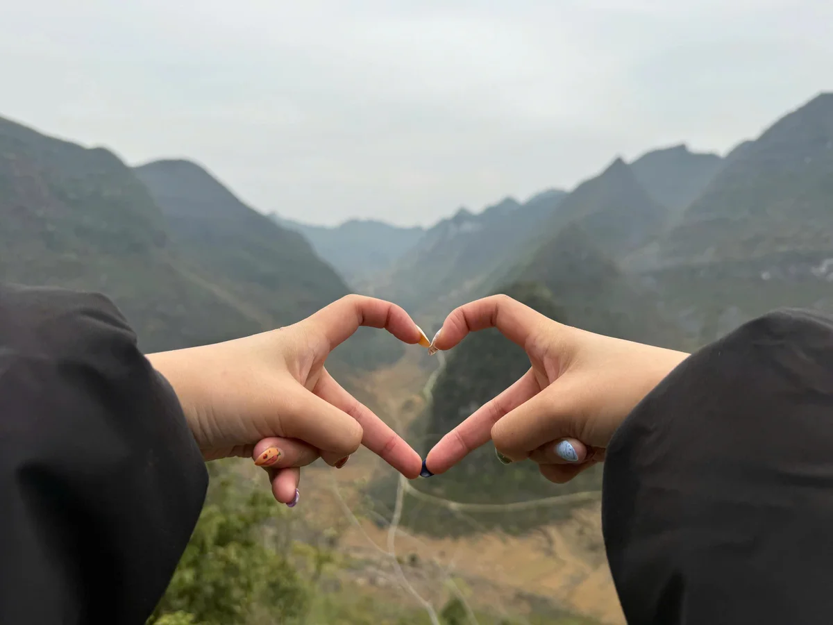 Girl creates heart shape with hands in Ha Giang