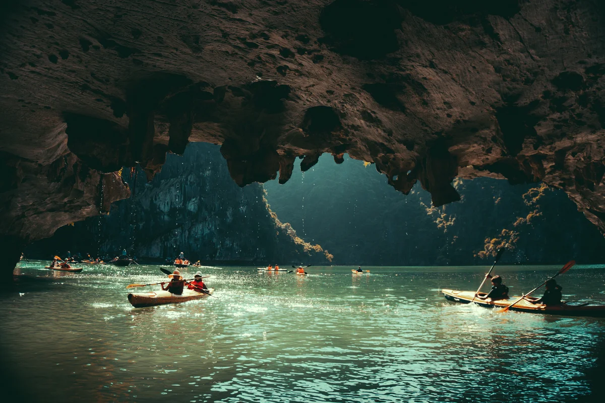 People paddling through a cave on kayaks