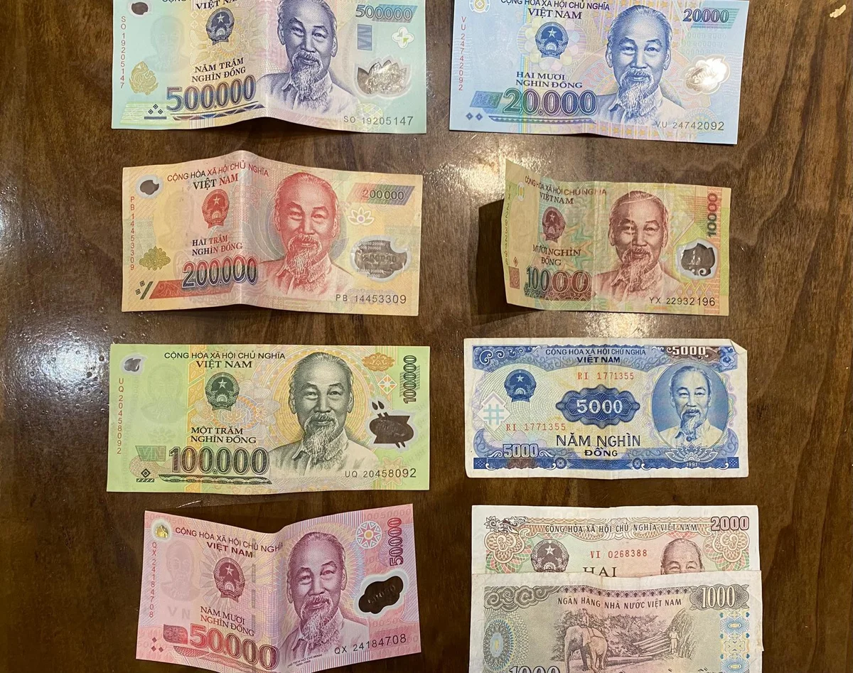 Vietnamese banknotes of various denominations, including 500,000, 200,000, 100,000, and 10,000 dong, displayed on a wooden surface.
