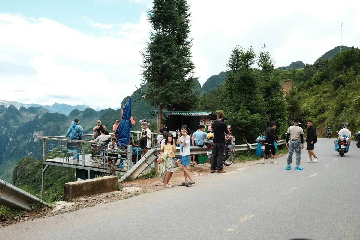 Children smiling at the camera, group of tourists in the background admiring the view